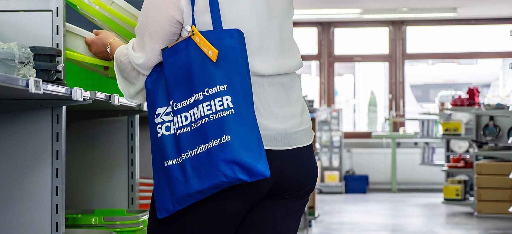 Eine Kundin beim Einkaufen im Zubehörshop von Caravaning Center Schmidtmeier und umgehängter Einkaufstasche.