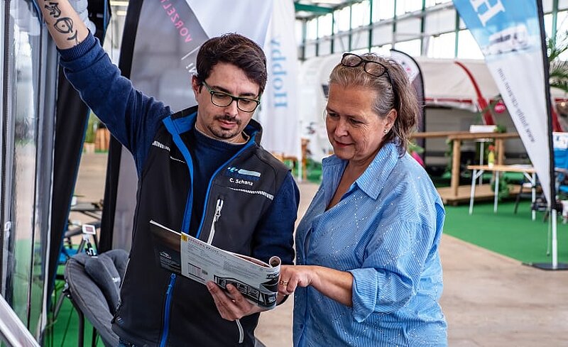Beratungsgespräch zwischen einem Mitarbeiter von Caravaning Center Schmidtmeier und einer interessierten Kundin an einem aufgebauten Zelt. Beratungsgespräch zwischen einem Mitarbeiter von Caravaning Center Schmidtmeier und einer interessierten Kundin an einem aufgebauten Zelt.